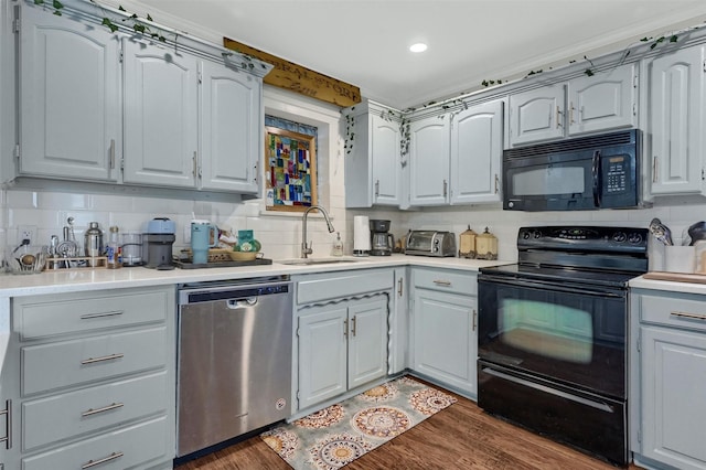 kitchen with black appliances, dark wood-type flooring, backsplash, and a sink