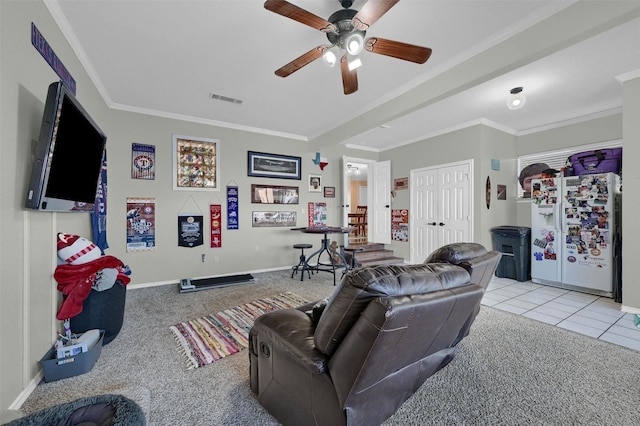 living area with visible vents, light carpet, crown molding, light tile patterned floors, and ceiling fan