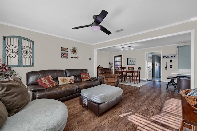 living area with visible vents, a ceiling fan, wood finished floors, crown molding, and baseboards