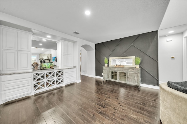 846 Underwood Ln, Celina, TX 75009 - living area featuring baseboards, arched walkways, dark wood-type flooring, a decorative wall, and an accent wall