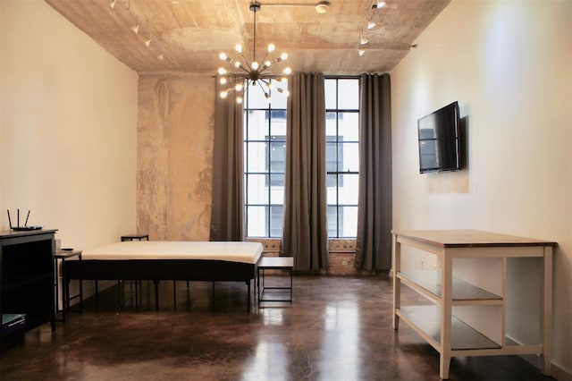 dining space featuring finished concrete flooring, track lighting, and a chandelier