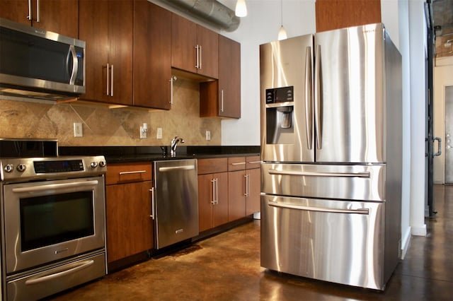 kitchen featuring a sink, tasteful backsplash, appliances with stainless steel finishes, and concrete flooring