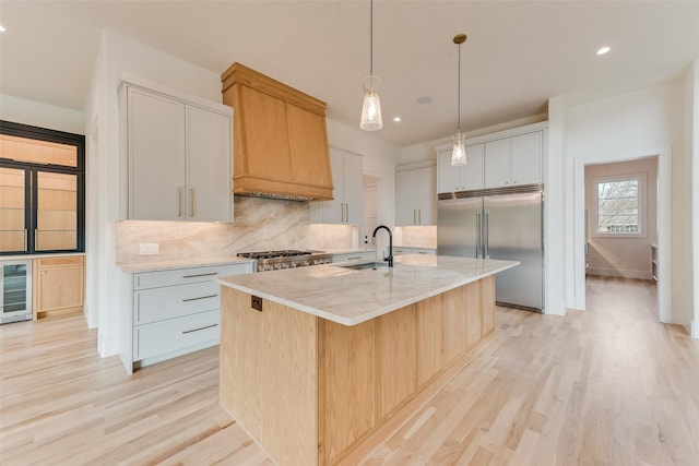 10519 Somerton Dr, Dallas, TX 75229 - kitchen featuring an island with sink, tasteful backsplash, a sink, light wood-style flooring, and stainless steel appliances