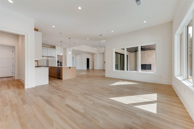 10519 Somerton Dr, Dallas, TX 75229 - unfurnished living room with recessed lighting, a healthy amount of sunlight, light wood-style flooring, and a fireplace