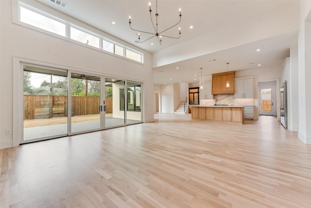 10519 Somerton Dr, Dallas, TX 75229 - unfurnished living room featuring stairway, a sink, light wood finished floors, a notable chandelier, and recessed lighting