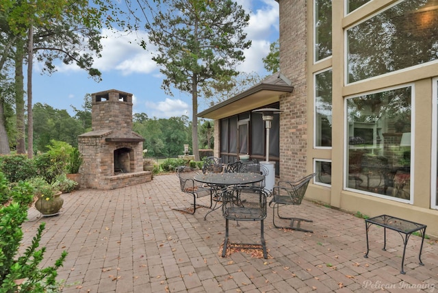 view of patio / terrace featuring outdoor dining area, a sunroom, and an outdoor brick fireplace