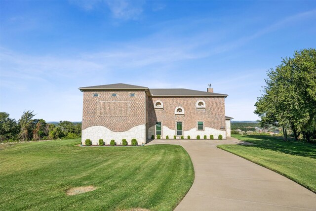 exterior space featuring brick siding, stone siding, a chimney, and a yard