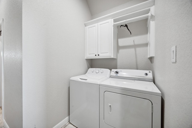 laundry area featuring cabinet space, washing machine and dryer, baseboards, and a textured wall