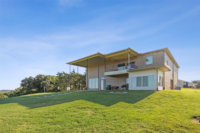 rear view of house with a yard, stucco siding, and a balcony