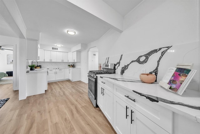 kitchen with gas stove, visible vents, light wood-style flooring, light countertops, and white cabinetry