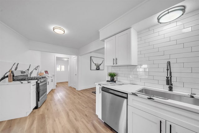 kitchen featuring a sink, appliances with stainless steel finishes, white cabinets, and crown molding