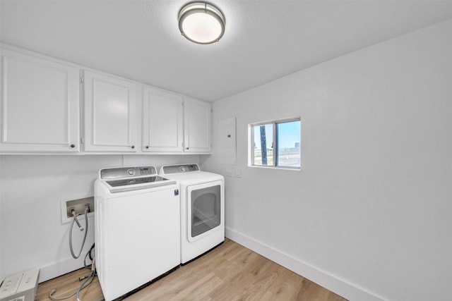 clothes washing area with light wood finished floors, baseboards, cabinet space, and washing machine and clothes dryer