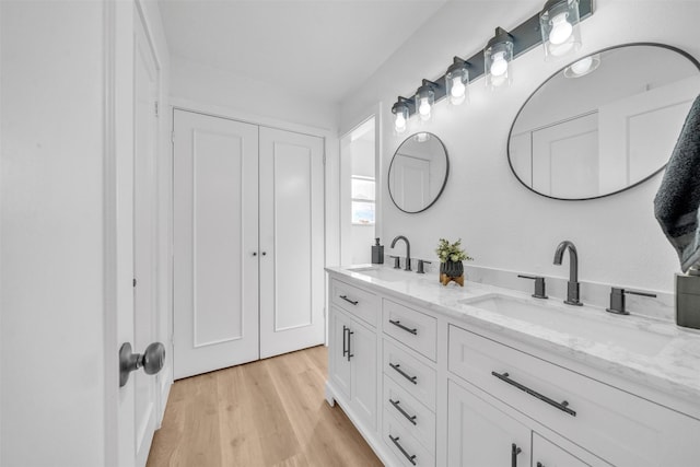 bathroom with double vanity, wood finished floors, and a sink
