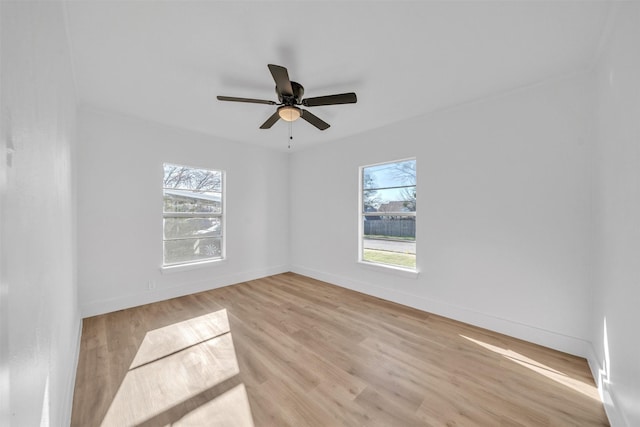 spare room with light wood finished floors, ceiling fan, and baseboards
