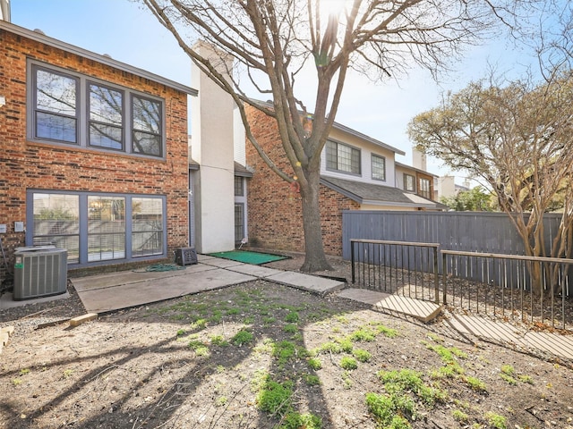 back of house featuring a patio, fence, brick siding, and central AC
