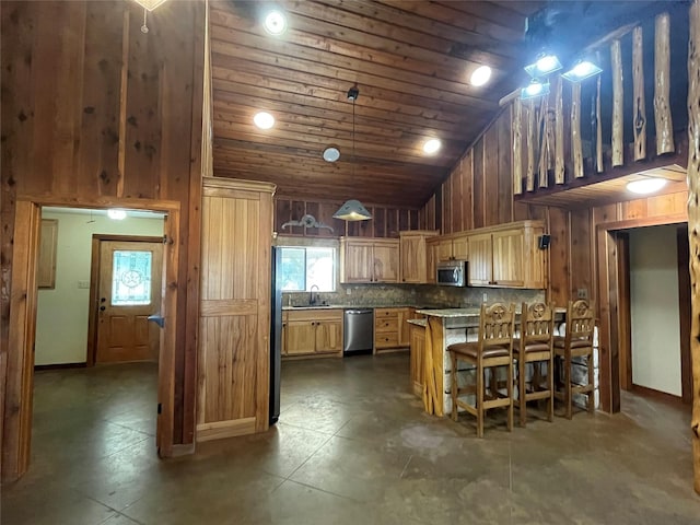 kitchen with wood walls, wood ceiling, a peninsula, stainless steel appliances, and high vaulted ceiling