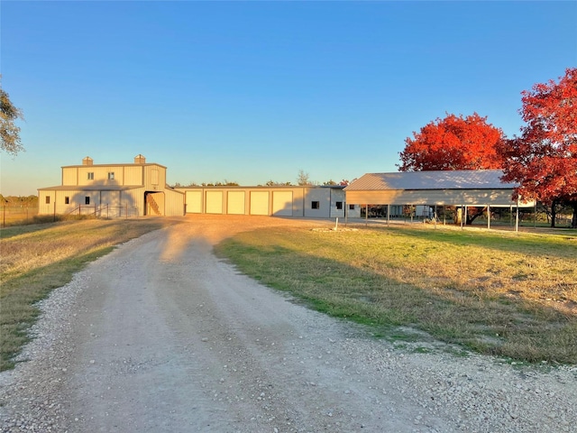 view of front of home featuring a garage, a chimney, and dirt driveway