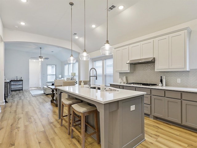 kitchen with a sink, a ceiling fan, under cabinet range hood, stainless steel gas stovetop, and gray cabinets