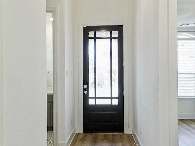 doorway to outside featuring baseboards, wood finished floors, and a healthy amount of sunlight