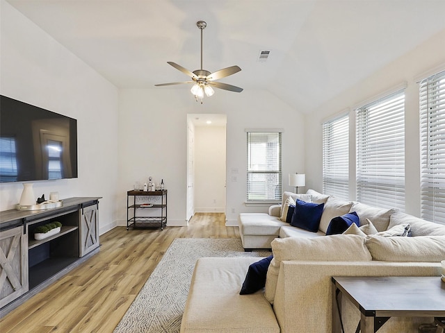 living area featuring baseboards, vaulted ceiling, a ceiling fan, visible vents, and light wood finished floors