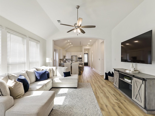 living room featuring arched walkways, ceiling fan, light wood finished floors, recessed lighting, and lofted ceiling