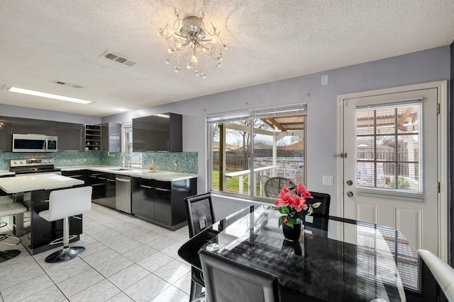 kitchen with light countertops, a sink, tasteful backsplash, stainless steel appliances, and visible vents