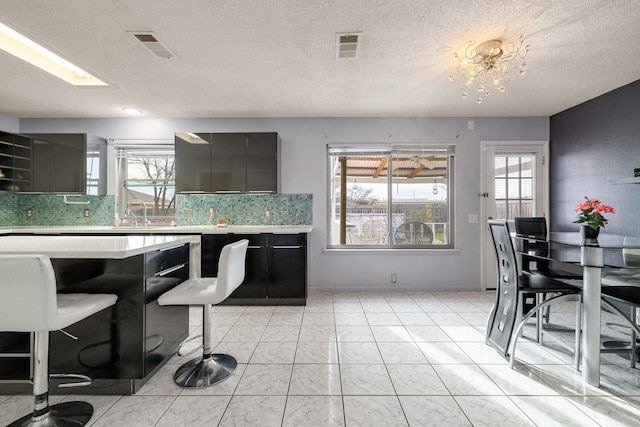 kitchen with modern cabinets, visible vents, light countertops, and backsplash