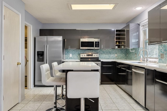 kitchen with light countertops, a kitchen bar, stainless steel appliances, a kitchen island, and a sink