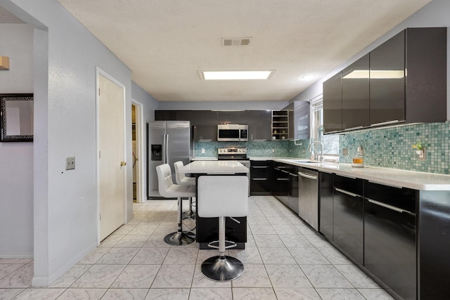 kitchen featuring backsplash, a kitchen breakfast bar, dark cabinetry, and stainless steel appliances