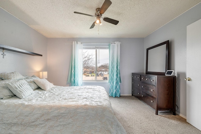 carpeted bedroom featuring baseboards, a textured ceiling, and a ceiling fan