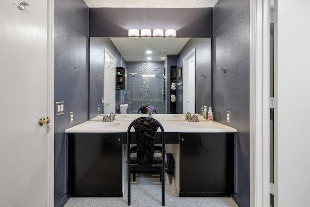 bathroom featuring a shower stall, a textured wall, and vanity