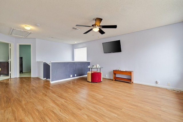 interior space featuring attic access, visible vents, light wood-style floors, and a ceiling fan