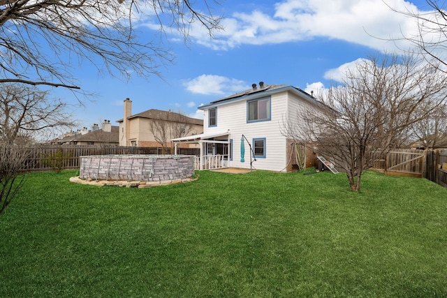 rear view of house featuring a fenced backyard, a fenced in pool, a patio area, and a yard