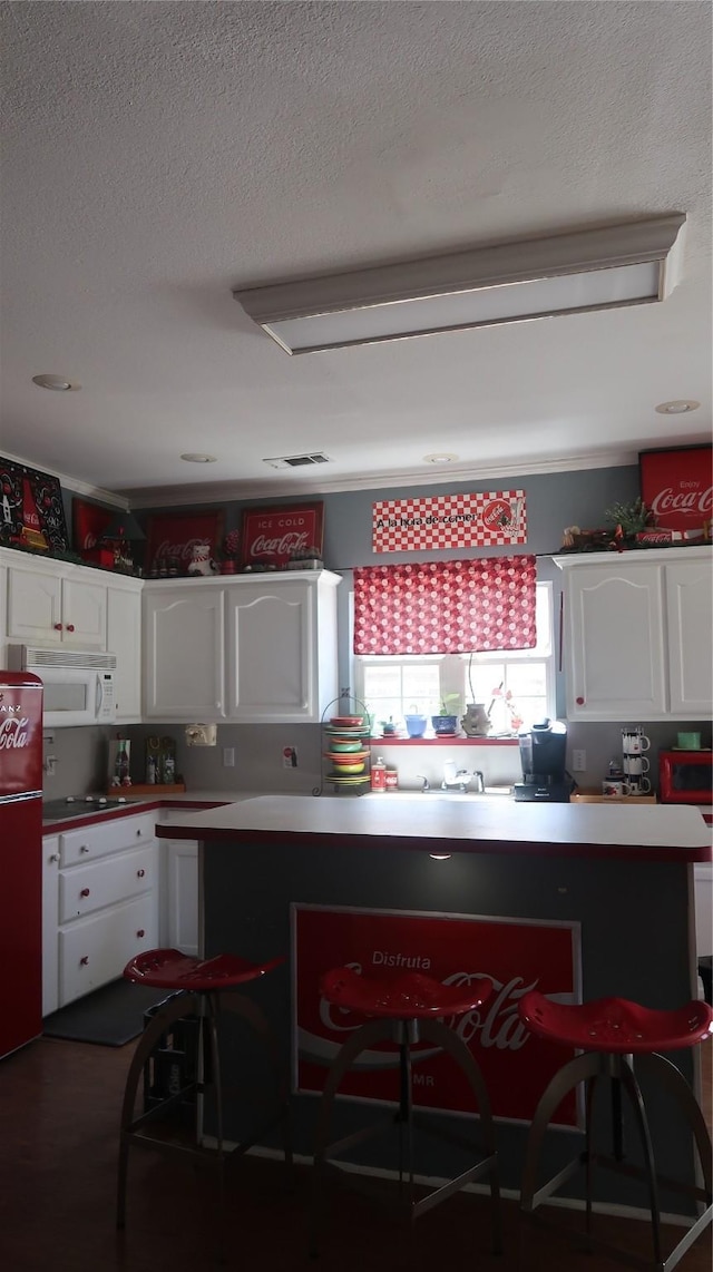 918 Wood St, Royse City, TX 75189 - kitchen with white cabinetry, a textured ceiling, fridge, visible vents, and white microwave
