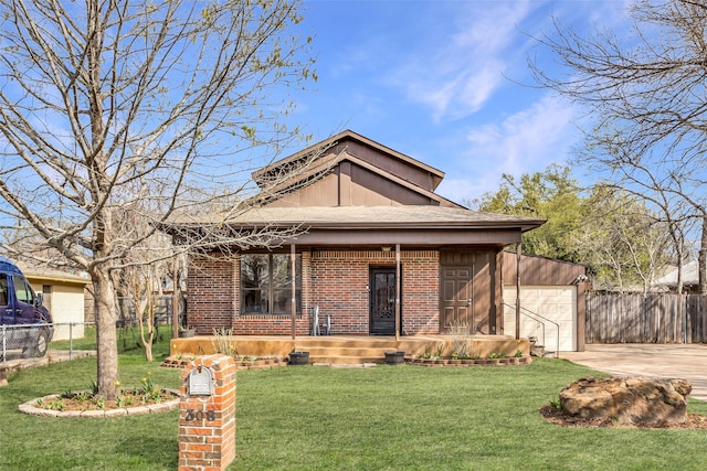 view of front of home featuring a front lawn, brick siding, driveway, and fence