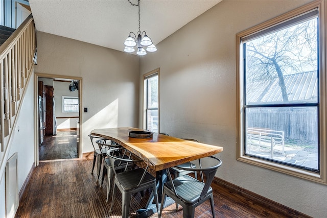 dining space featuring a notable chandelier, lofted ceiling, dark wood-type flooring, and stairs