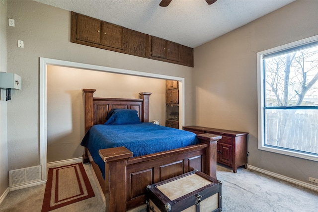 bedroom with visible vents, light carpet, a textured ceiling, and baseboards