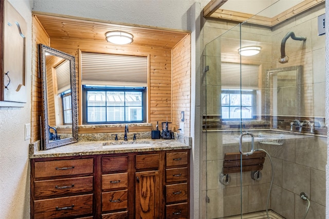 full bathroom with vanity, a shower stall, and a textured wall