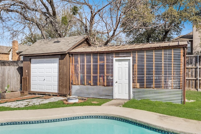 exterior space with an outbuilding, a garage, a fenced in pool, and fence