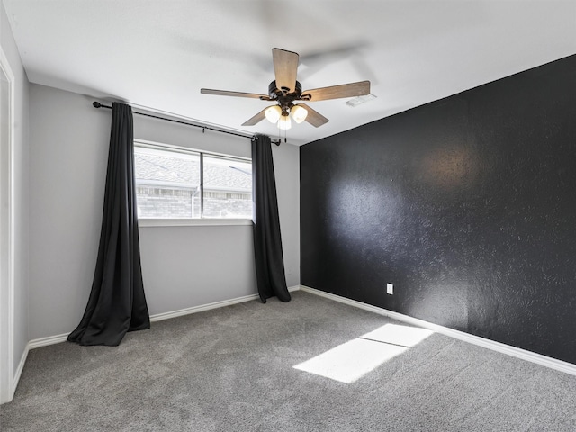 spare room featuring carpet floors, ceiling fan, and baseboards