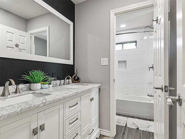 full bathroom featuring double vanity, wood finished floors, shower / washtub combination, and baseboards