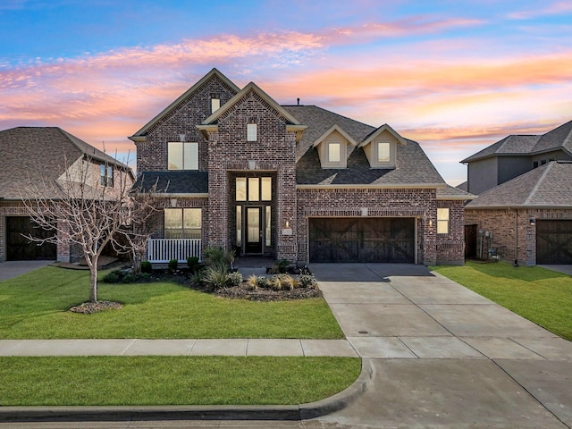 view of front facade featuring a lawn, a garage, driveway, and brick siding