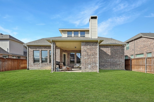 back of house with a fenced backyard, a patio, a chimney, and a yard