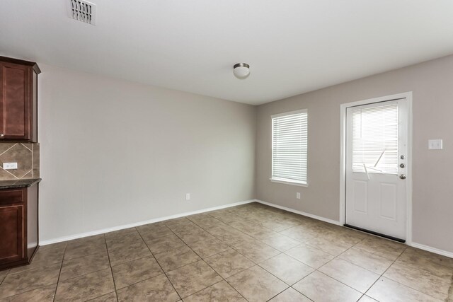 unfurnished dining area featuring light tile patterned floors, visible vents, and baseboards