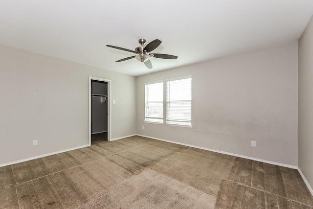 carpeted spare room with a ceiling fan and baseboards