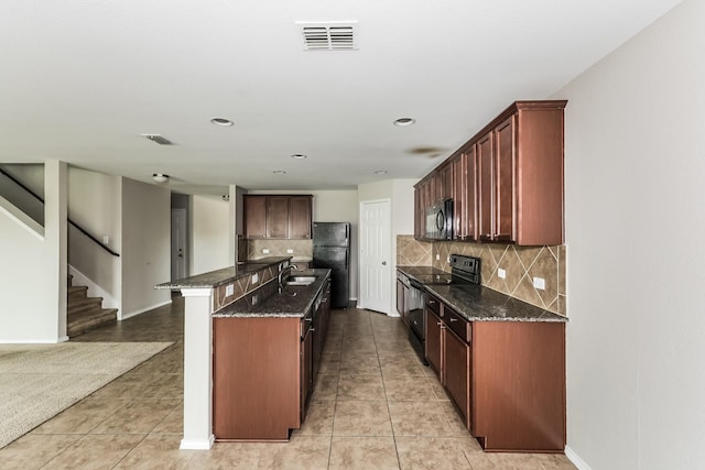 kitchen with dark stone countertops, visible vents, black appliances, and light tile patterned flooring