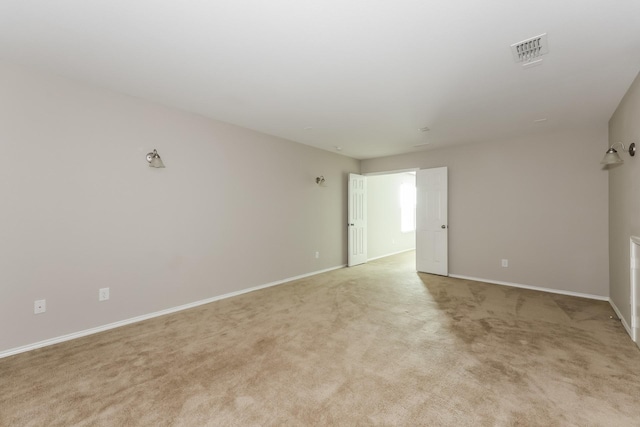 spare room featuring light colored carpet, visible vents, and baseboards