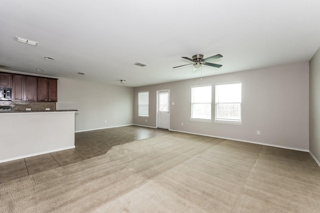 unfurnished living room with tile patterned floors, visible vents, carpet flooring, baseboards, and ceiling fan