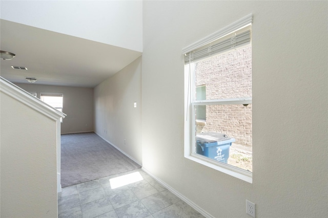 hall featuring baseboards, visible vents, and carpet floors