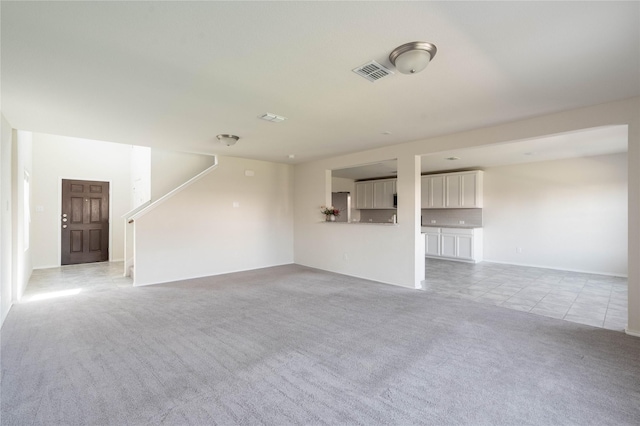 unfurnished living room featuring stairway, light tile patterned floors, light colored carpet, and visible vents
